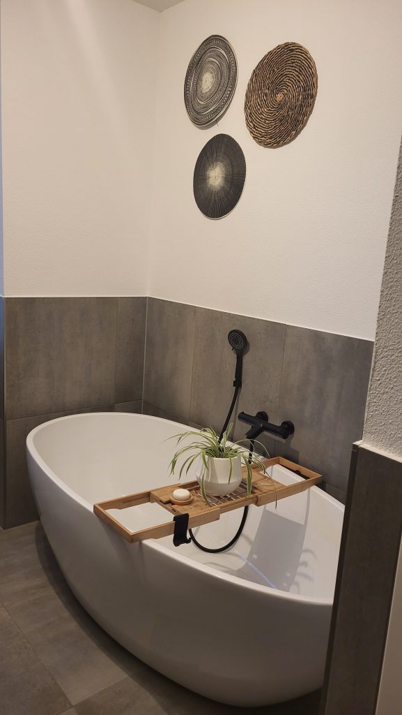 Vrijstaand bad. Badkamer met grijze tegels.